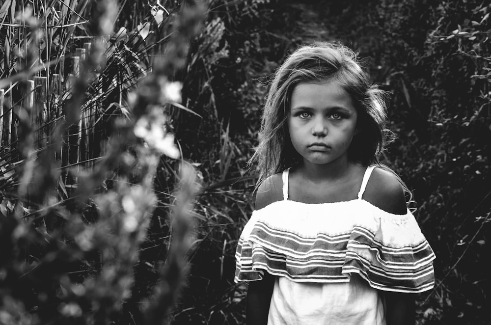 Foto en escala de grises de una niña en el jardín