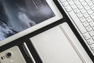 a tablet, a pen, and a notebook on a desk