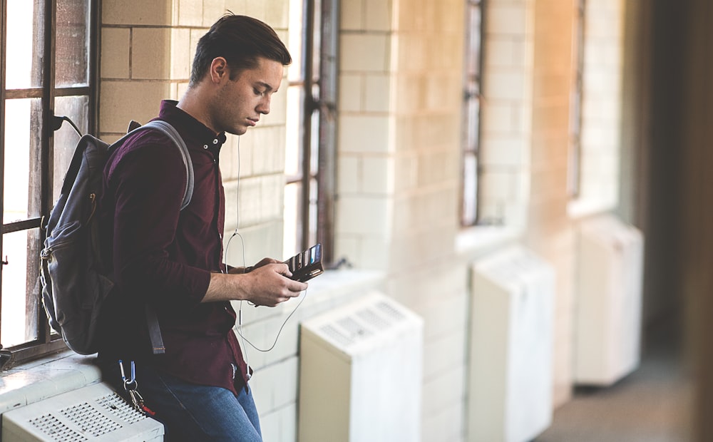 man leaning while holding leather wallet