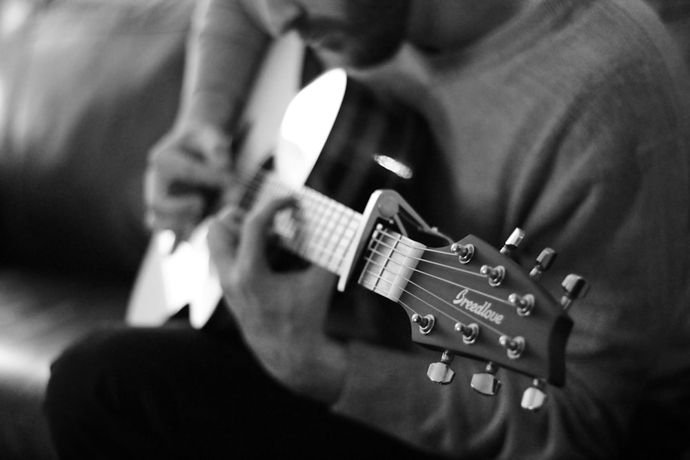 homem que toca a foto da escala de cinza da guitarra