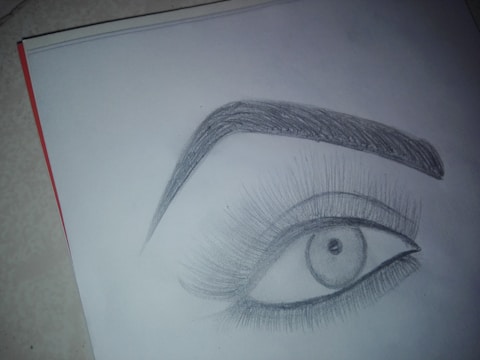 Close-up of a detailed pencil sketch showing expressive human eyes and subtle shading.