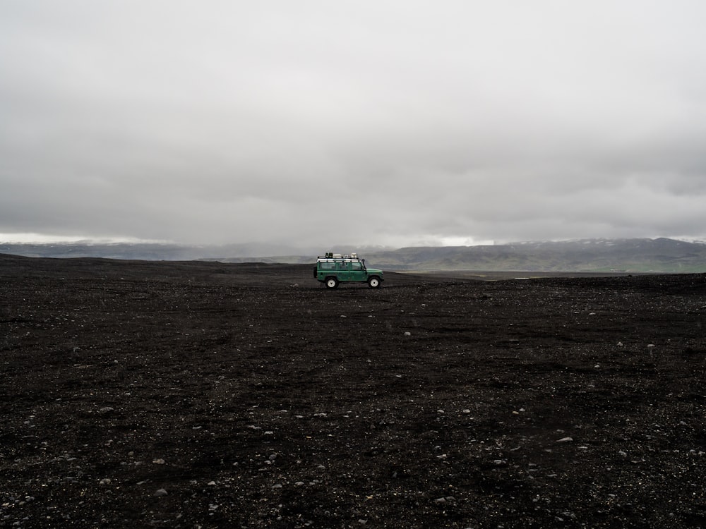 昼間に撮影した黒い土の上の緑色のSUV