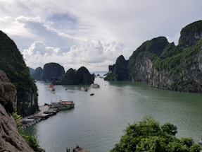 A vibrant photo of Halong Bay at sunrise with limestone karsts reflecting on calm water.