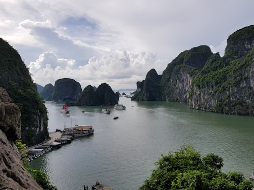 A vibrant photo of Halong Bay at sunrise with limestone karsts reflecting on calm water.