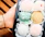 Close-up of hands holding a tray of assorted gourmet geladinhos with vibrant colors