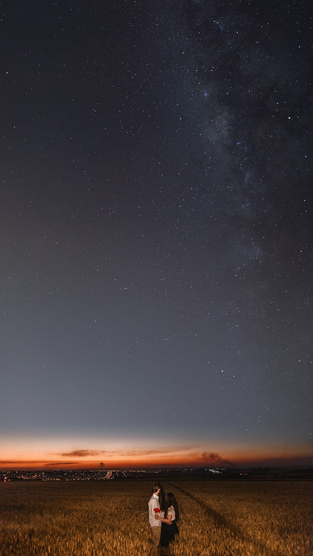 man and woman standing near grass field at nighttime