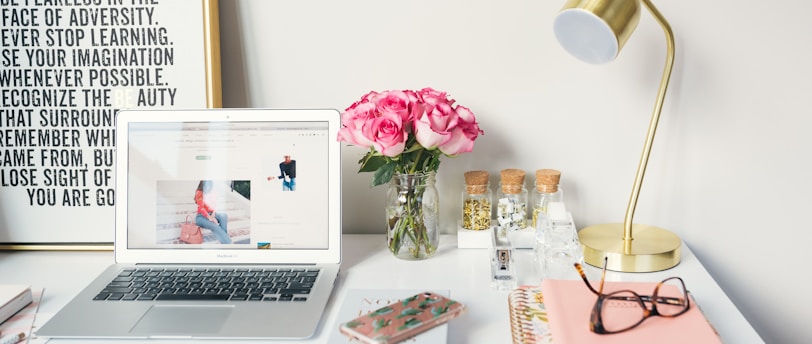 MacBook Air beside gold-colored study lamp and spiral books