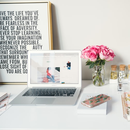 MacBook Air beside gold-colored study lamp and spiral books