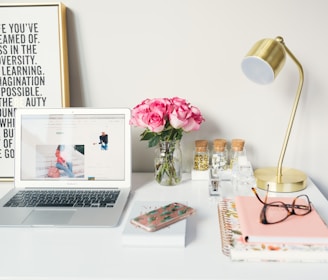 MacBook Air beside gold-colored study lamp and spiral books