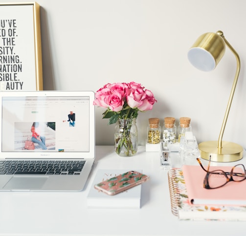 MacBook Air beside gold-colored study lamp and spiral books