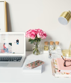 MacBook Air beside gold-colored study lamp and spiral books