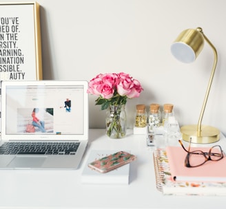 MacBook Air beside gold-colored study lamp and spiral books