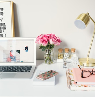 MacBook Air beside gold-colored study lamp and spiral books