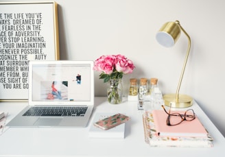 MacBook Air beside gold-colored study lamp and spiral books