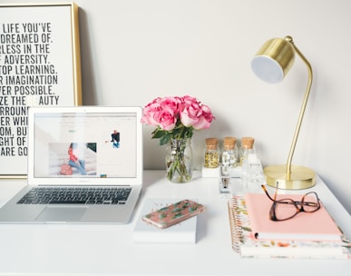 MacBook Air beside gold-colored study lamp and spiral books