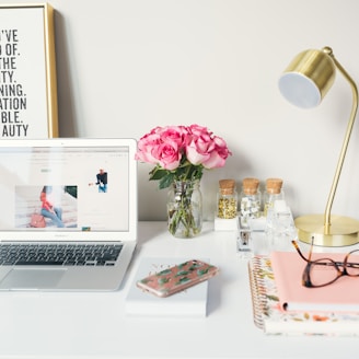 MacBook Air beside gold-colored study lamp and spiral books