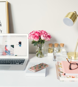 MacBook Air beside gold-colored study lamp and spiral books