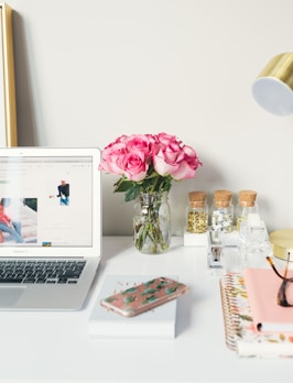 MacBook Air beside gold-colored study lamp and spiral books