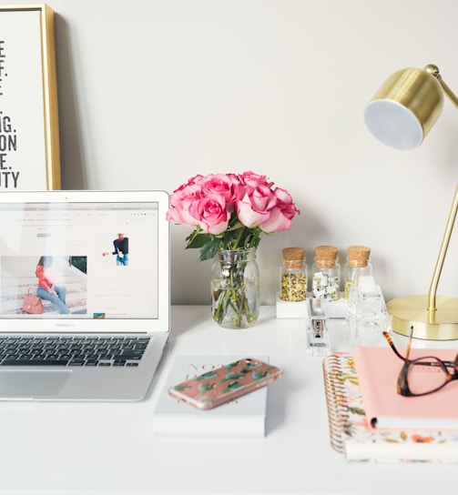 MacBook Air beside gold-colored study lamp and spiral books