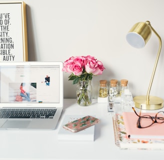 MacBook Air beside gold-colored study lamp and spiral books