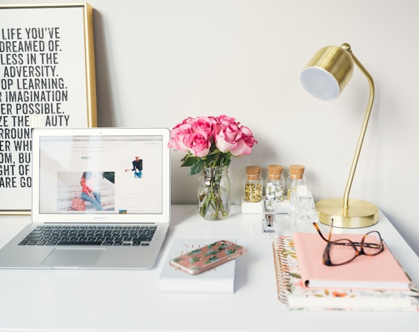 MacBook Air beside gold-colored study lamp and spiral books