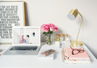 MacBook Air beside gold-colored study lamp and spiral books