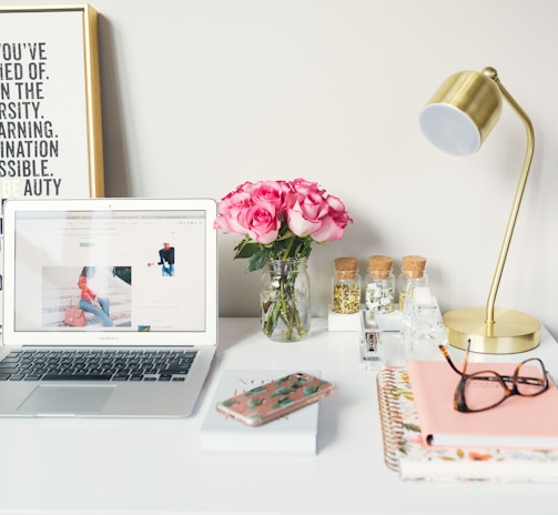 MacBook Air beside gold-colored study lamp and spiral books