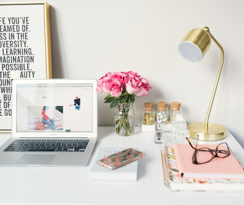 MacBook Air beside gold-colored study lamp and spiral books