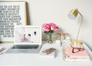 MacBook Air beside gold-colored study lamp and spiral books