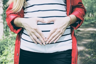 a mother-to-be in red jacket making heart illustration