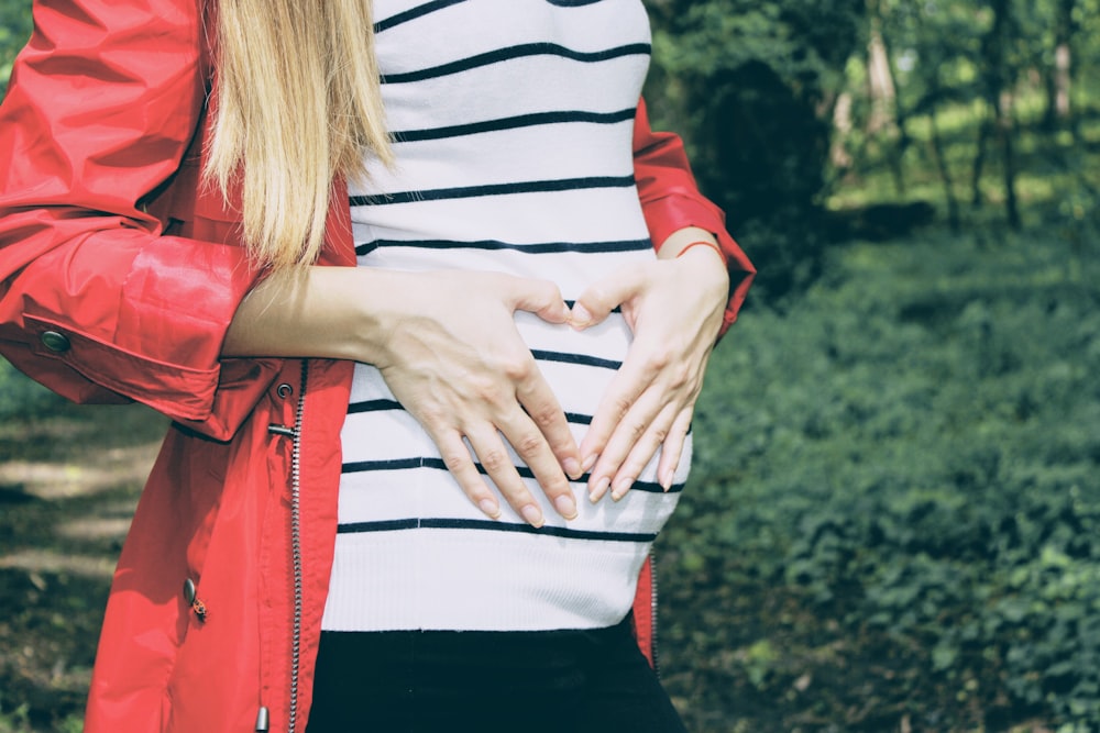 woman forming heart on her womb during daytime