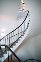 A sleek black metal staircase spiraling upward in a modern office space.