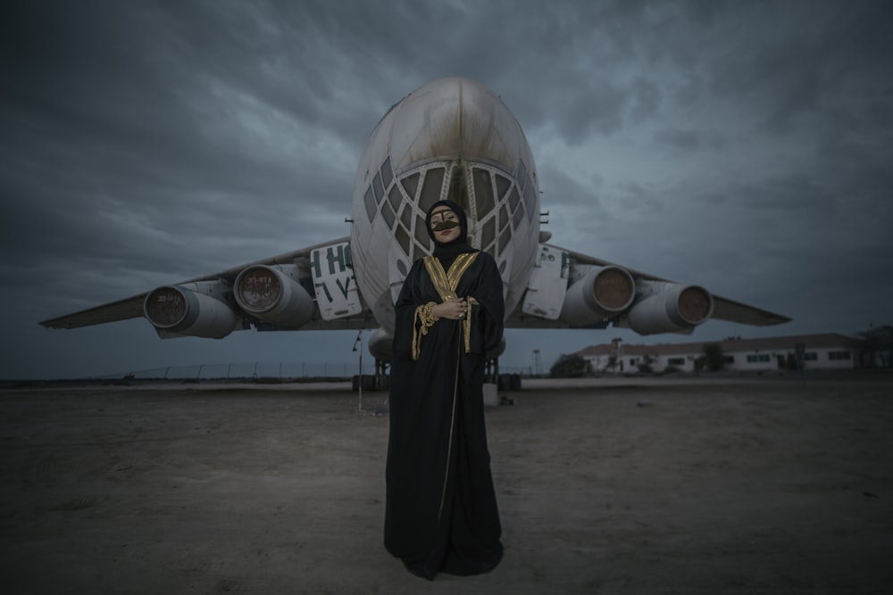 mulher usando vestido preto em pé perto do avião branco