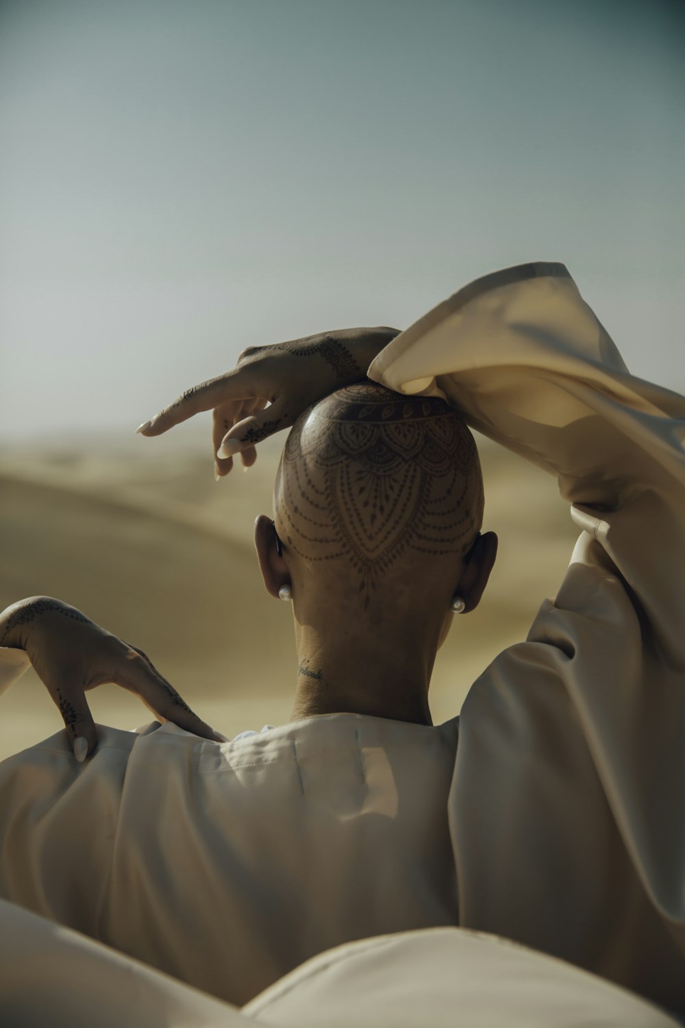 bald woman wearing white top holding her head