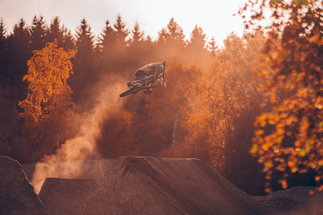 a person on a dirt bike in the air, Watching the leaves turning brown and the sun getting down.