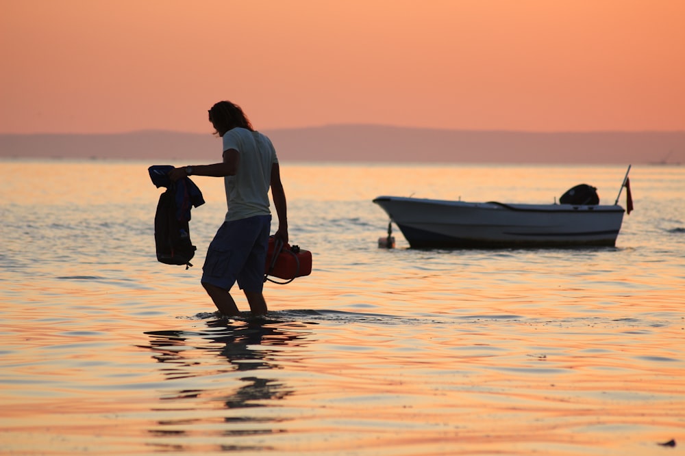 man walking on shore during sunset