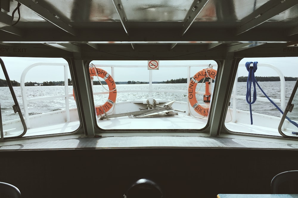 clear glass ship windshield in front of two orange swim rings during daytime