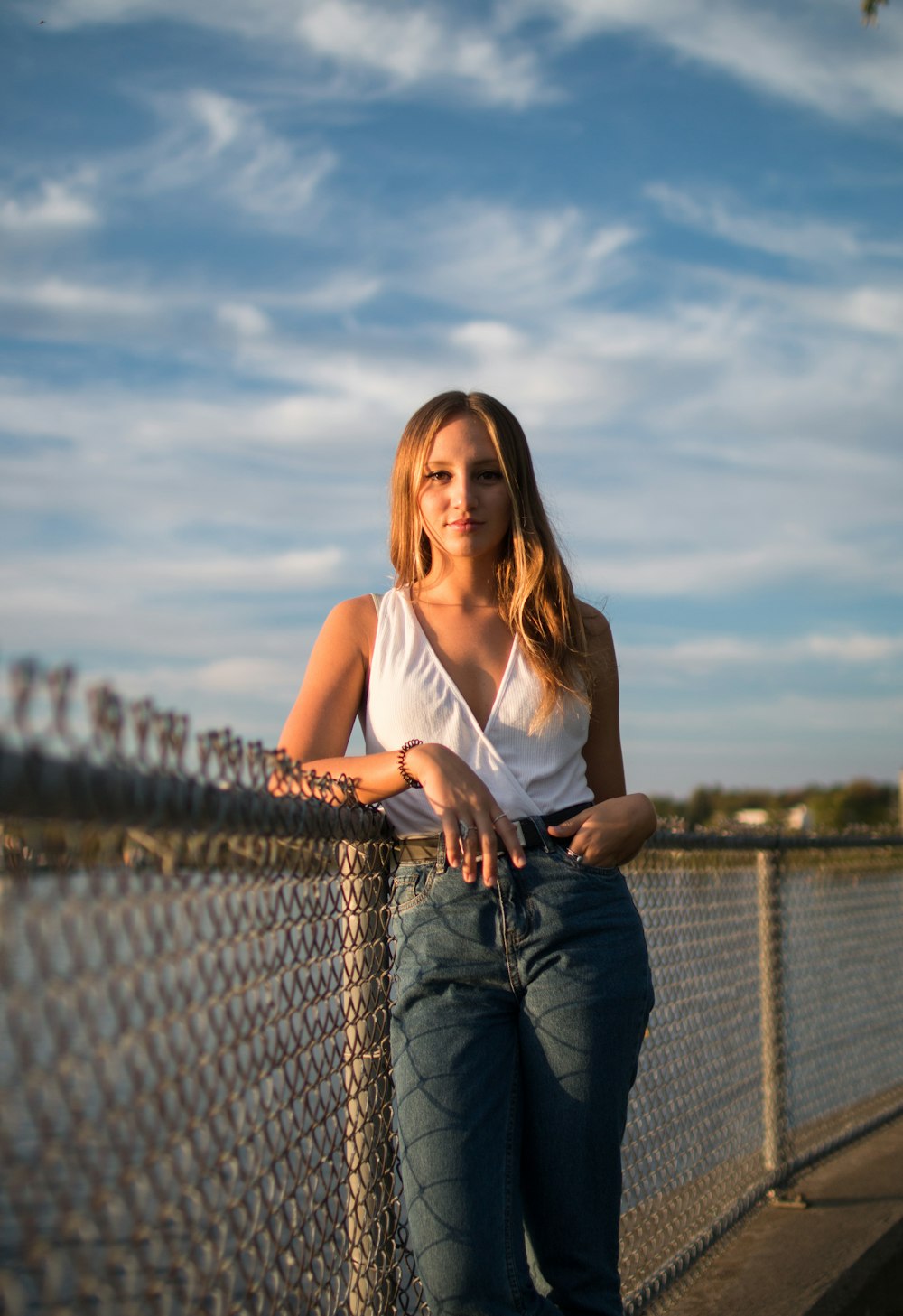 selective focus photography of standing woman leaning on chain link fence during daytime