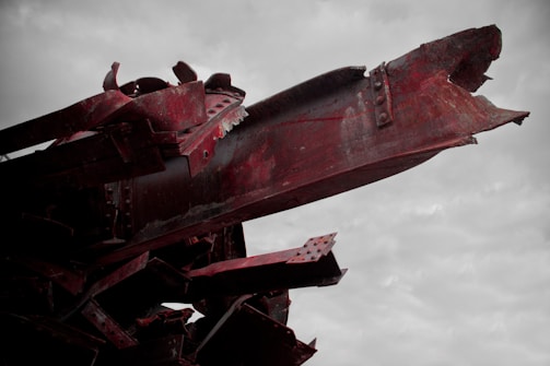 Rusty metal scraps scattered across a neglected landscape under a cloudy sky.