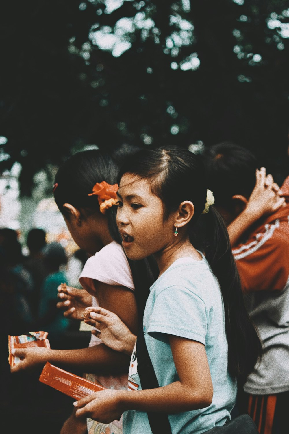 several children eating snack under shade of tree