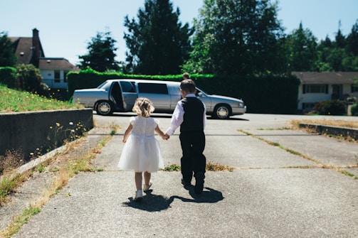 boy and girl walking on gray road during daytime