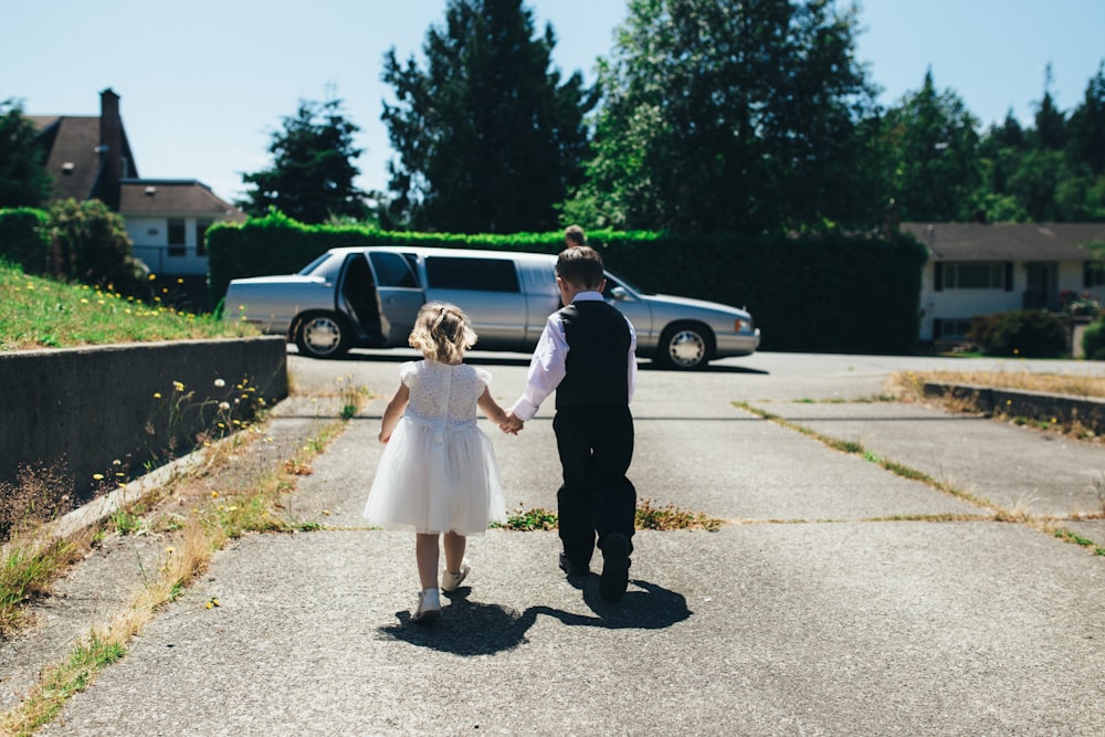 boy and girl walking on gray road during daytime