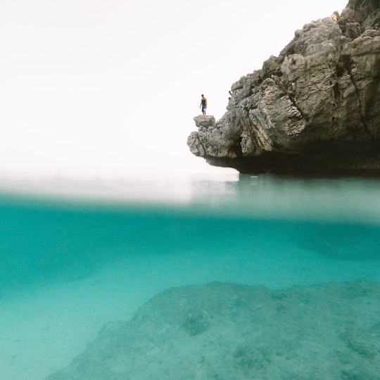 man standing on gray rock mountain in front of body of water during daytime in Fortune Island Philippines