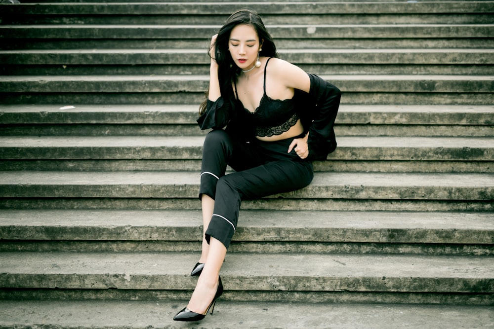 woman wearing black bralette, jacket, and capri pants posing on stairs