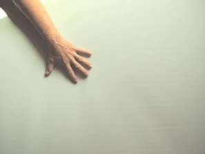 Soft-focus image of calm hands resting on a white surface with subtle shadows.