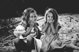 grayscale photography of two girls closing their mouths