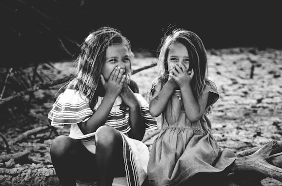 grayscale photography of two girls closing their mouths
