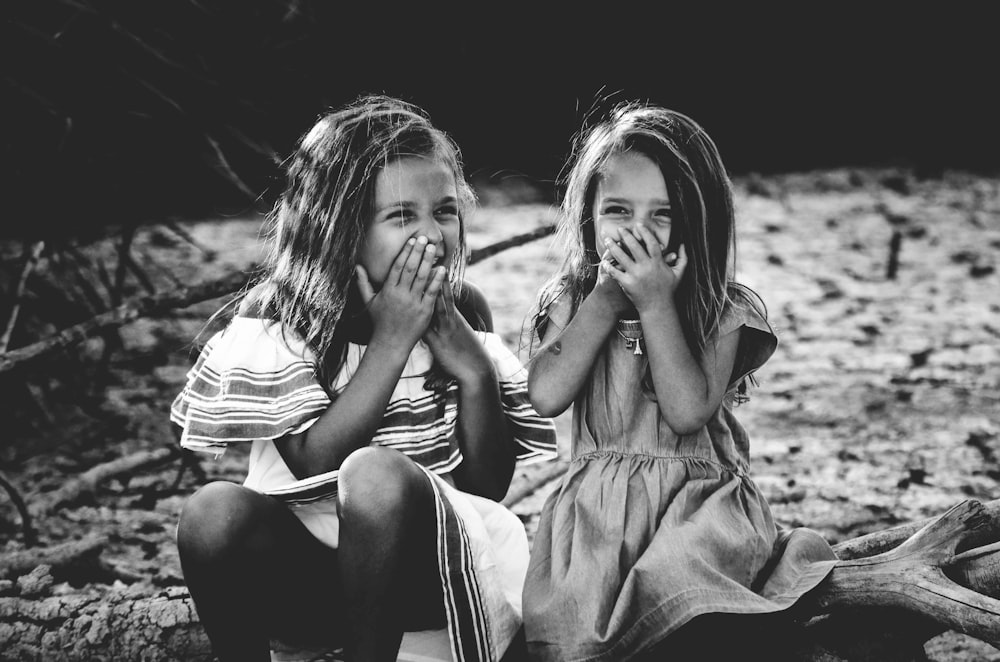 grayscale photography of two girls closing their mouths