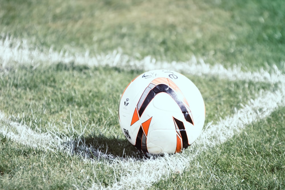 Balón de fútbol blanco, naranja y negro en el campo