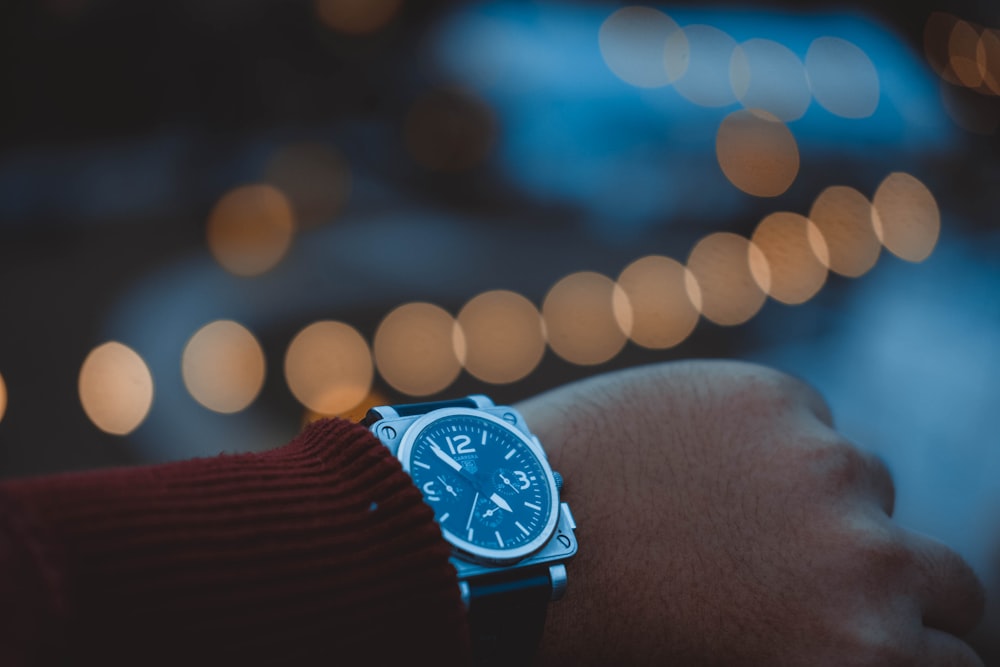 bokeh photography person wearing round silver-colored chronograph watch